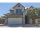 Front exterior of a two-story home featuring a two-car garage, neutral paint, and tidy landscaping with a mature tree at 41581 W Somerset Dr, Maricopa, AZ 85138