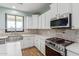 Modern kitchen with stainless steel appliances, white cabinets, and decorative backsplash at 41581 W Somerset Dr, Maricopa, AZ 85138