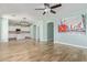 Open-concept living area with wood-look tile floors, light blue walls, modern lighting, and an arched entryway to the kitchen at 41581 W Somerset Dr, Maricopa, AZ 85138