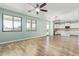 Open living room featuring wood-look flooring, ceiling fan, and access to the bright kitchen at 41581 W Somerset Dr, Maricopa, AZ 85138