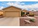 Charming home featuring a well-maintained front yard, tan stucco, a two-car garage, and decorative desert landscaping at 42911 W Magic Moment Dr, Maricopa, AZ 85138