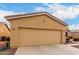 A tan home showing the two-car garage with decorative circles above the door, and desert landscaping in the front yard at 42911 W Magic Moment Dr, Maricopa, AZ 85138