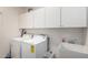 Well-organized laundry room with white cabinets, a sink, and modern washing machine and dryer at 42911 W Magic Moment Dr, Maricopa, AZ 85138