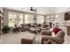 A comfortable living room featuring neutral decor, a ceiling fan, and an open concept flowing into the dining and kitchen areas at 42911 W Magic Moment Dr, Maricopa, AZ 85138