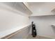 A well-organized walk-in closet with built-in shelving and a golf bag on the carpeted floor at 42911 W Magic Moment Dr, Maricopa, AZ 85138