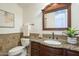 Bathroom featuring a dark wood vanity with granite countertop, decorative mirror, and tiled walls at 4576 E Waterman St, Gilbert, AZ 85297