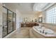 Elegant bathroom with large soaking tub, travertine floors, wood cabinets, and glass block window at 4576 E Waterman St, Gilbert, AZ 85297