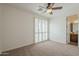 Bright bedroom features neutral carpeting, ceiling fan, and natural light offering access to an ensuite bathroom at 4576 E Waterman St, Gilbert, AZ 85297