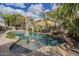 Beautiful backyard pool with mature landscaping, rock waterfall feature, and sunny skies at 4576 E Waterman St, Gilbert, AZ 85297
