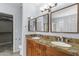 Bathroom featuring double sinks with granite countertops, wood cabinets and walk-in closet at 5755 W Harrison St, Chandler, AZ 85226