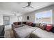 An open-concept living room with an oversized sectional couch, ceiling fan, and multiple windows at 6225 W Mary Jane Ln, Glendale, AZ 85306