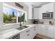 Close-up on a modern kitchen with white cabinets, stainless steel appliances, and a backyard view at 7435 E Corrine Rd, Scottsdale, AZ 85260