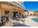 Inviting covered patio with lounge chairs, offering a serene outdoor space overlooking the sparkling pool and lush landscaping at 9363 E Mendoza Ave, Mesa, AZ 85209