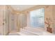 Well-lit primary bathroom features a soaking tub, glass block window, and glass enclosed shower at 10421 N 100Th St, Scottsdale, AZ 85258