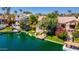 Exterior waterfront view of a home with a dock, lush landscaping, and charming architectural details at 10421 N 100Th St, Scottsdale, AZ 85258