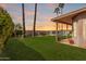 Green backyard featuring palm trees, desert landscaping, a fence, and covered patio at 10563 E Bella Vista Dr, Scottsdale, AZ 85258