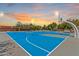 A brightly painted basketball court with hoops and benches, illuminated by evening lights at 10563 E Bella Vista Dr, Scottsdale, AZ 85258