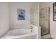 A bathtub with white tile surround is lit by a window and features glass block accents and a shower at 10563 E Bella Vista Dr, Scottsdale, AZ 85258