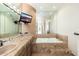 Bright bathroom featuring a tiled tub with mounted TV, vanity and a glass-enclosed shower area at 10707 E Cottontail Ln, Scottsdale, AZ 85255