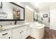 Elegant bathroom with white cabinetry, a granite countertop, a soaking tub, and a glass block window at 11352 E Starkey Ave, Mesa, AZ 85212