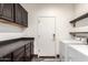 This laundry room features dark wood cabinets, floating shelves, and a new white washer and dryer at 11831 W Daley Ct, Sun City, AZ 85373