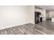 Open-concept living area with gray wood floors, black refrigerator, and white cabinets creates a modern, seamless flow at 11831 W Daley Ct, Sun City, AZ 85373