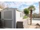 Backyard view featuring a tidy storage shed near a lush pool and stone planter boxes at 13487 E Gold Dust Ave, Scottsdale, AZ 85259