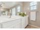 Bright bathroom vanity with white cabinets, tile floors, and a large mirror at 1548 W Windhaven Ave, Gilbert, AZ 85233