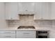 Close-up of a modern kitchen with stainless steel gas range, white cabinets, and a stylish backsplash at 1548 W Windhaven Ave, Gilbert, AZ 85233