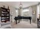 Living room features a grand piano, decorative chandelier, and an abundance of natural light at 1548 W Windhaven Ave, Gilbert, AZ 85233