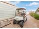 White golf cart parked on a paved driveway with blue skies overhead and mature landscaping at 17200 W Bell Rd # 2125, Surprise, AZ 85374