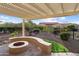 Backyard features a pergola, gravel landscaping, colorful plants, and a unique stone fire pit seating area at 21854 N 263Rd Dr, Buckeye, AZ 85396