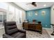 Inviting home office with blue accent wall, wooden desk, and comfortable reading chair near bright window at 21854 N 263Rd Dr, Buckeye, AZ 85396