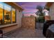 Cozy outdoor patio with stone accent wall, wrought iron gate, and comfortable seating area at dusk at 21854 N 263Rd Dr, Buckeye, AZ 85396