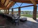 Covered patio features stone columns, wood beams, comfortable seating, and views of the lake and lush landscaping at 24275 N 173Rd Ave, Surprise, AZ 85387