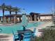 Community pool with sun loungers and umbrellas, offering a relaxing oasis with palm trees and clear blue water at 24275 N 173Rd Ave, Surprise, AZ 85387