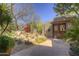 Desert landscape features a waterfall, cactus, and mature trees leading to a wooden gate and hacienda-style home at 3119 Arroyo Hondo --, Carefree, AZ 85377