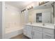 Well-lit bathroom with double sinks, white cabinets, and tub and shower combination at 4053 W Quail Ave, Glendale, AZ 85308