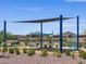 Community playground with swings, a shade structure and walking paths in a landscaped Gathering neighborhood at 41740 W Sonoran Trl, Maricopa, AZ 85138