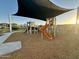 Vibrant playground with colorful equipment and a protective shade canopy, set on a mulch surface at 9819 W Agora Ln, Tolleson, AZ 85353