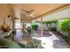 Relaxing covered patio featuring a ceiling fan, seating, and a brick-paved area with mature trees and landscaping at 10443 W Loma Blanca Dr, Sun City, AZ 85351