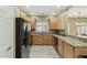 Well-lit kitchen featuring granite counters, light wood cabinets, and black appliances at 14000 N 94Th St # 2144, Scottsdale, AZ 85260