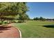 Picturesque park with walking path, green grass, and mature shade trees under a clear blue sky at 17200 W Bell Rd # 77, Surprise, AZ 85374