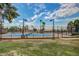 Well-maintained tennis court with blue surface, surrounded by a fence and lush green grass at 17200 W Bell Rd # 77, Surprise, AZ 85374