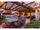 Outdoor dining area beneath a grand pergola, overlooking a pristine pool, putting green, and barbecue for the ultimate space at 17541 W Statler Dr, Surprise, AZ 85388