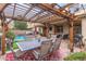 Outdoor dining area beneath a grand pergola, overlooking a pristine pool and putting green for the ultimate entertainment space at 17541 W Statler Dr, Surprise, AZ 85388