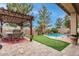 Landscaped backyard featuring a pergola-covered patio, putting green, and inviting pool, perfect for entertaining and relaxation at 17541 W Statler Dr, Surprise, AZ 85388
