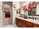 Bathroom showcasing a double vanity with wood cabinets, granite counters, and decorative mirrors at 17541 W Statler Dr, Surprise, AZ 85388
