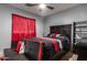 Modern bedroom with a black bed frame, red accents, and a comfortable seating area at 17541 W Statler Dr, Surprise, AZ 85388