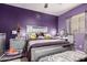 A stylish purple bedroom with a mirrored bed frame, modern furniture, and ample natural light at 17541 W Statler Dr, Surprise, AZ 85388